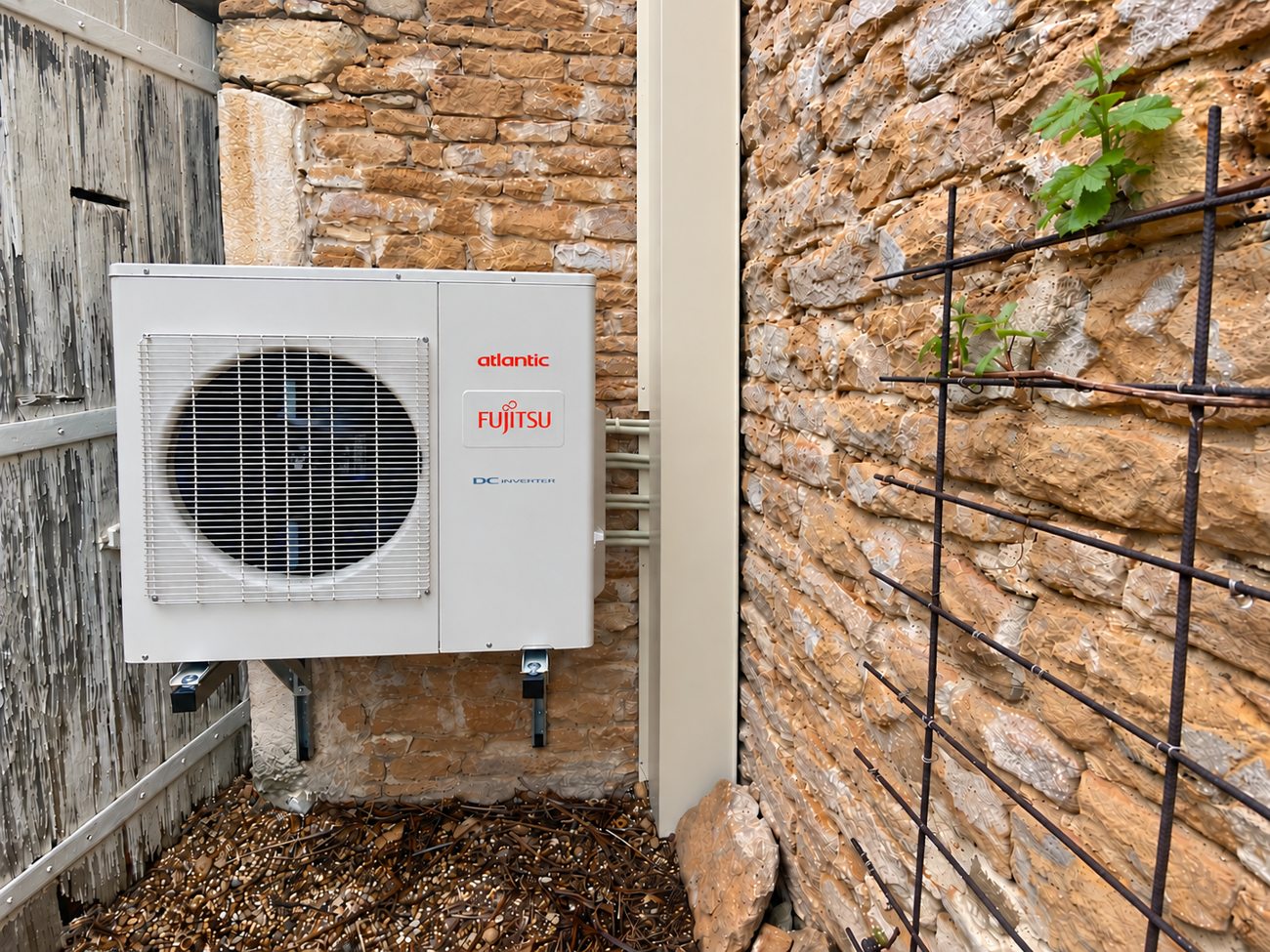 Groupe extérieur de climatisation Atlantic Fujitsu installé sur un mur en pierre